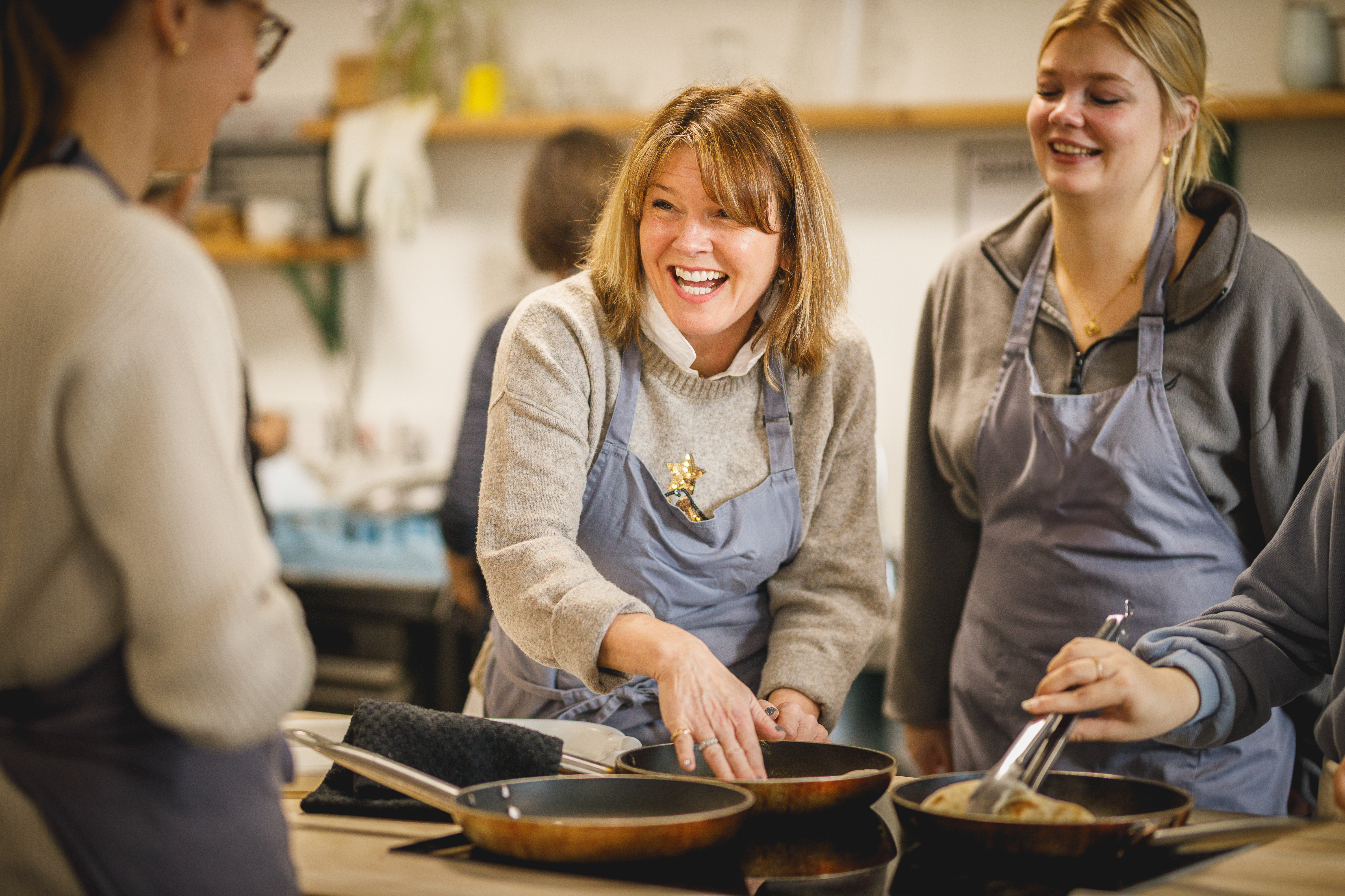 Three people frying flatbreads together in kitchen and smiling.jpg