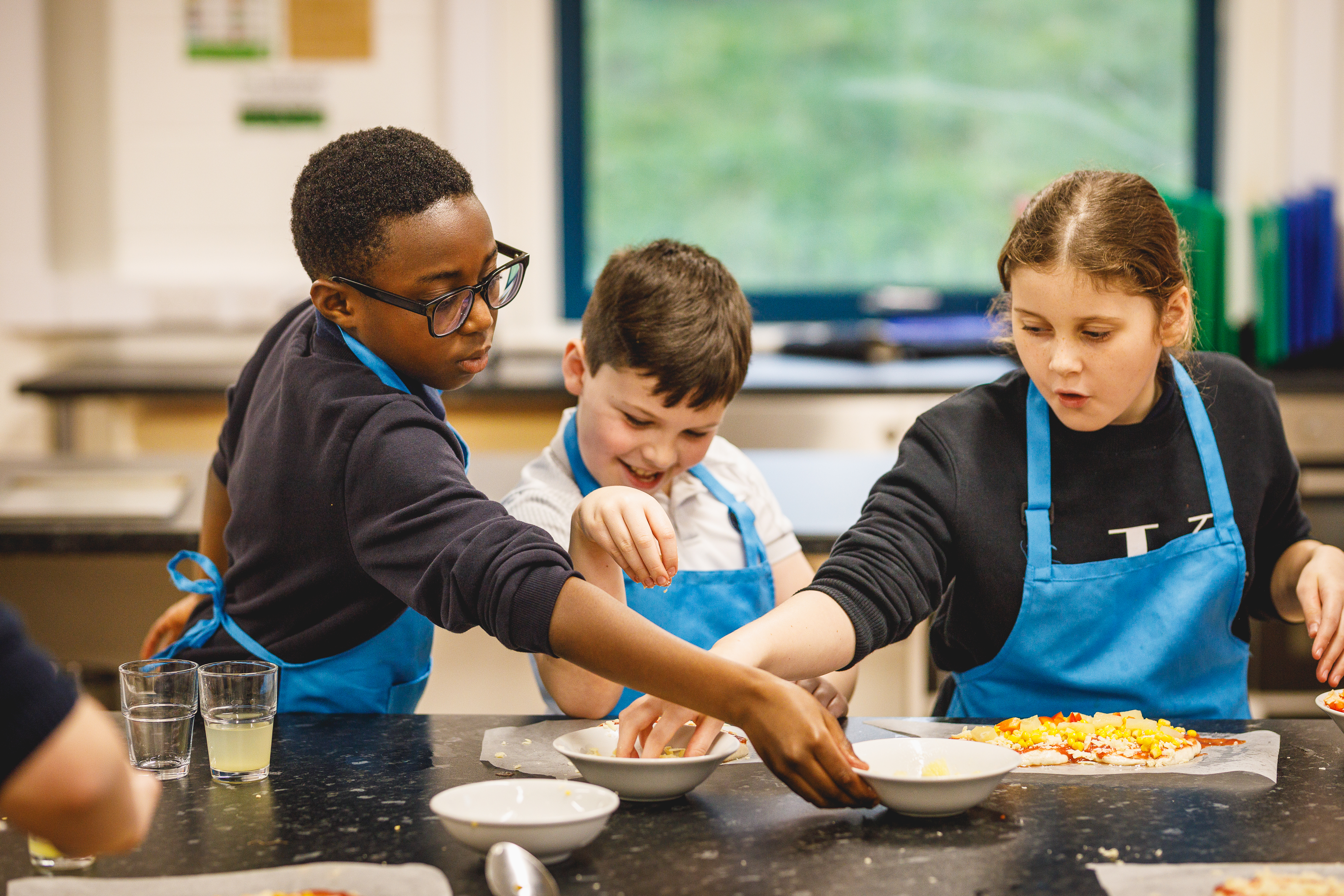 Three children putting toppings on a pizza.jpg