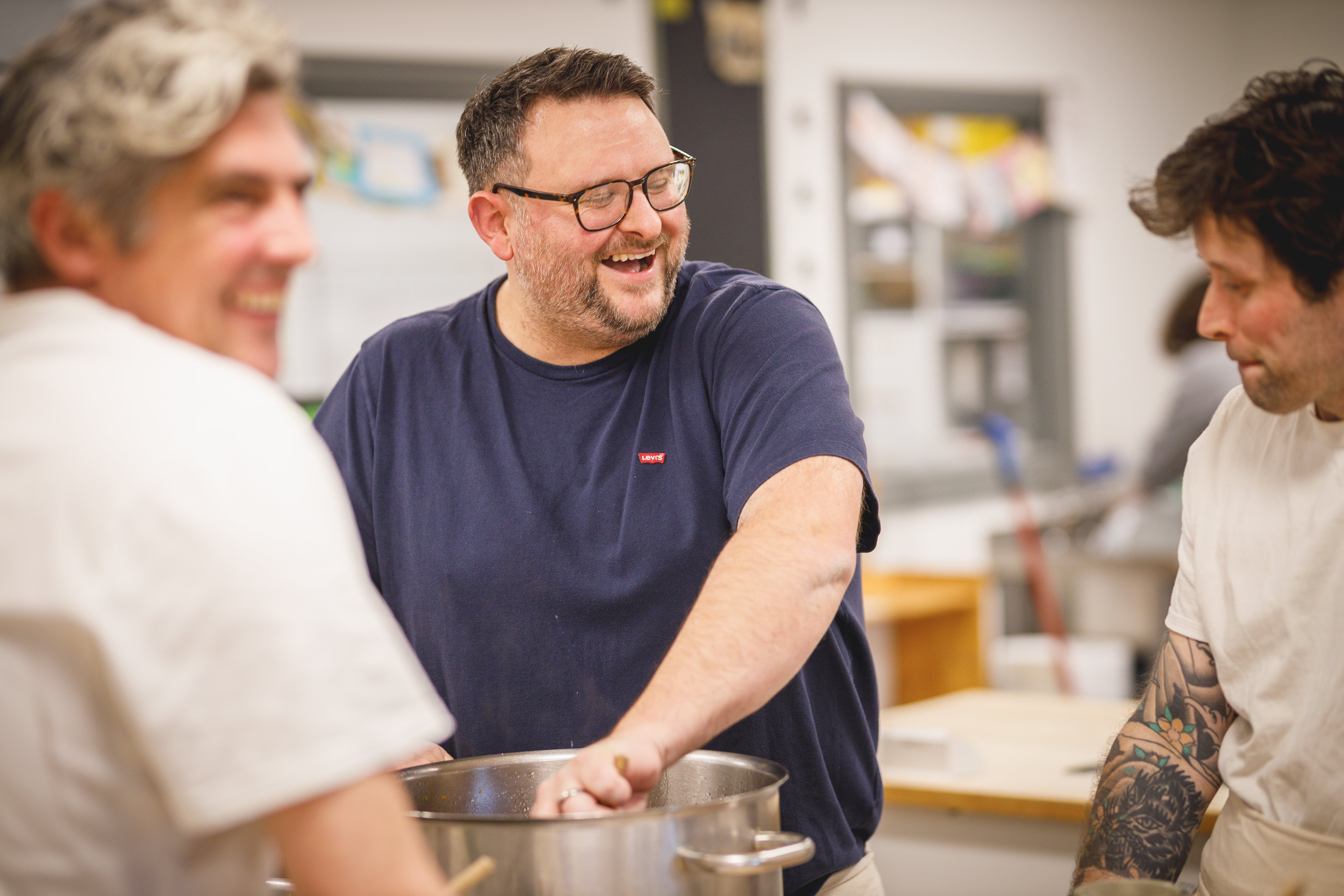 Three chefs laughing together in the kitchen while cooking.jpg